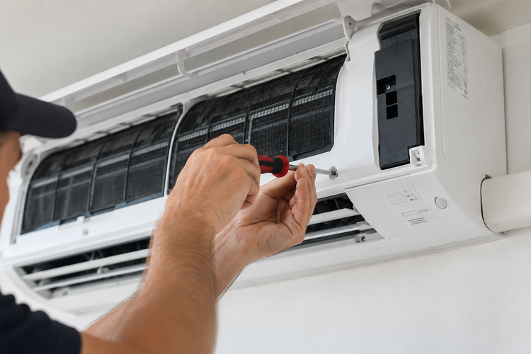 A Tovan engineer servicing a wall-mounted air conditioning unit